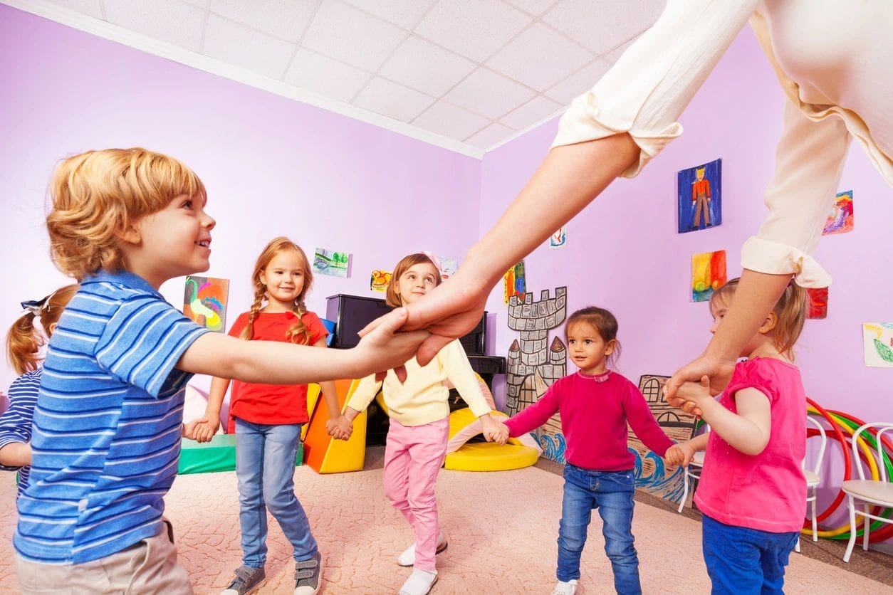 A group of children holding hands in a room.