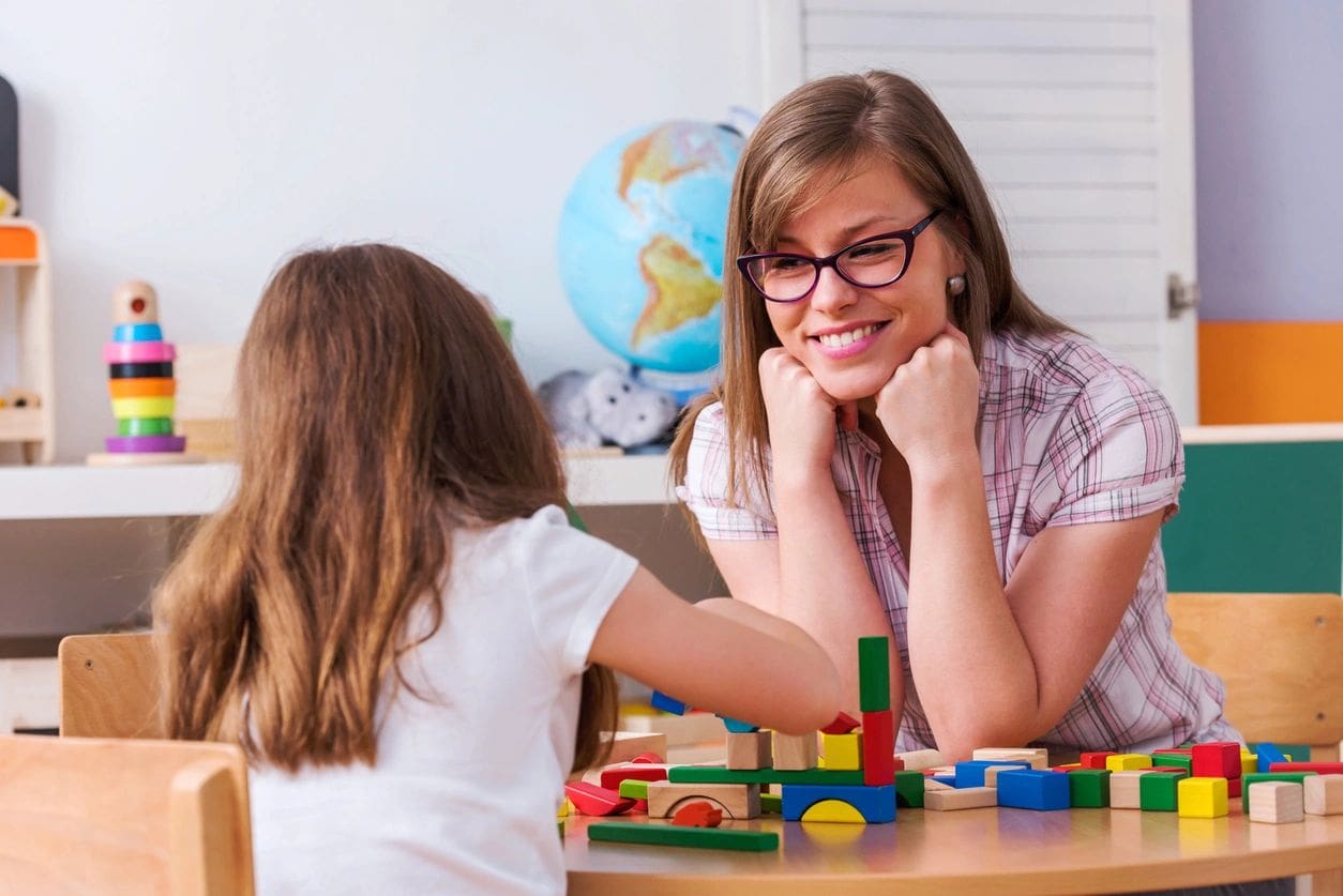 A woman and girl sitting at a table with blocks.