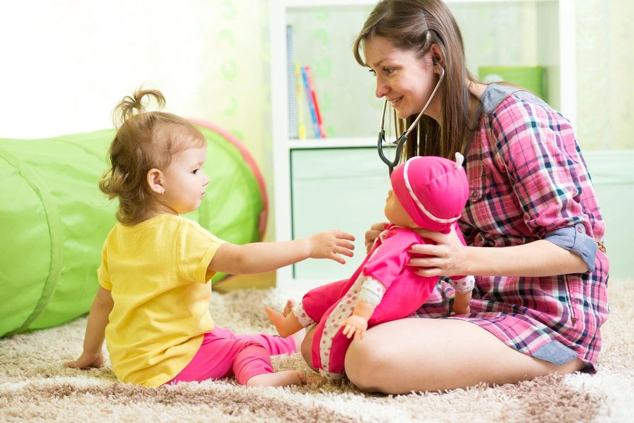 A woman and child playing with a doll.